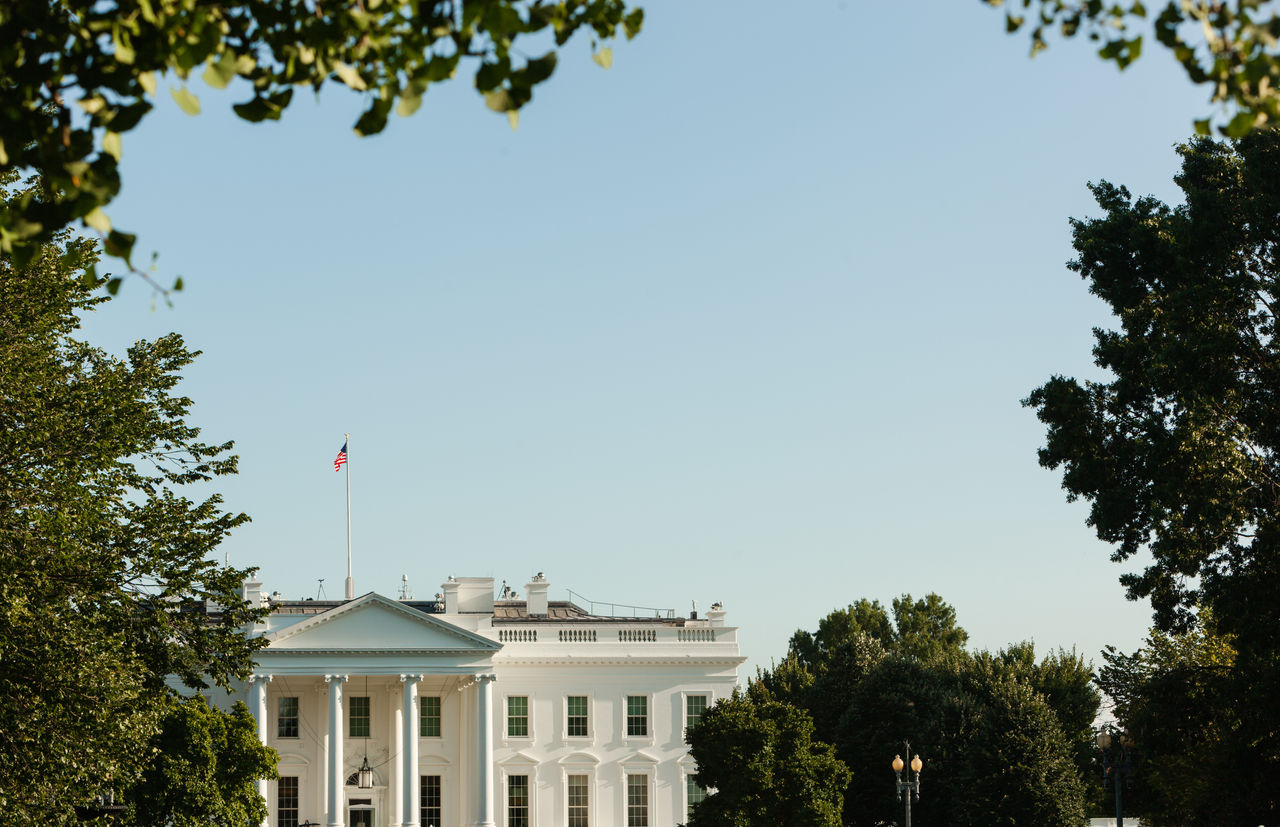 Washington, USA - August 09 2019: The White House Building in Evening Light on a sunny Day with blue Sky, framed with Trees  and with Copy Space